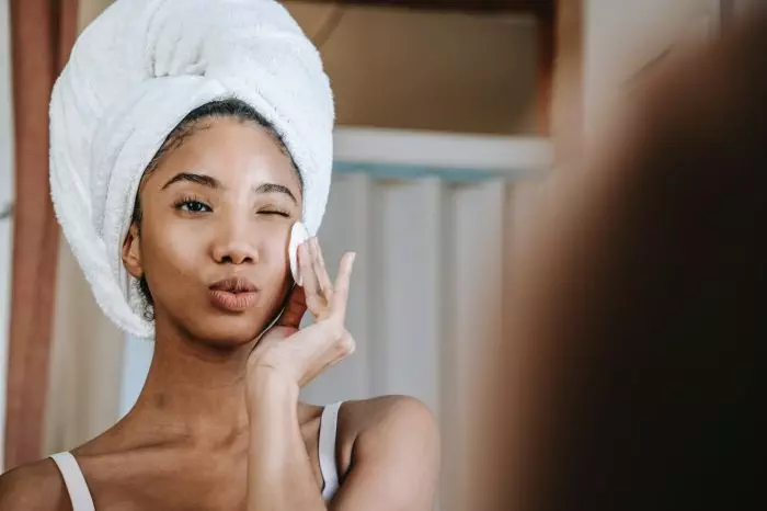 Woman doing skincare in front of miirror scaled 1